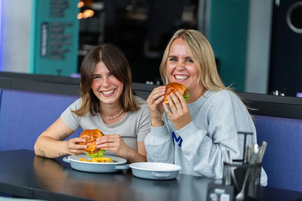 Zwei Frauen essen Burger im JIMIS Bistro